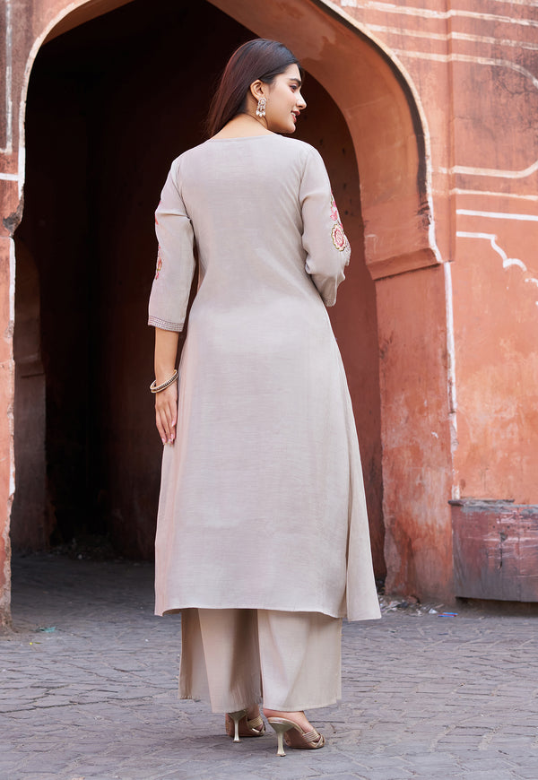 Woman in a beige kurta with palazzo pants standing in front of an archway.