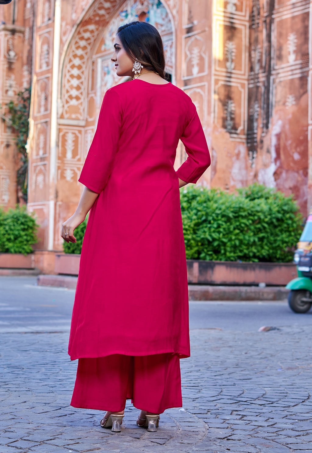 Woman in a red outfit standing in front of an architectural building.