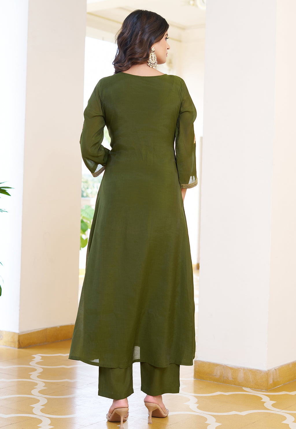 Woman wearing a green kurta with matching pants in an indoor setting.