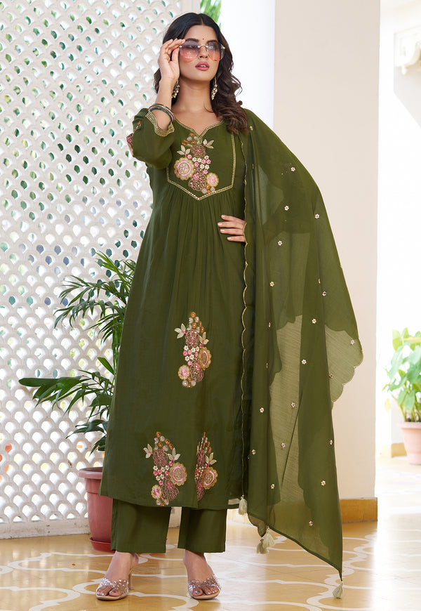 Woman wearing a green embroidered outfit with a dupatta in an indoor setting.