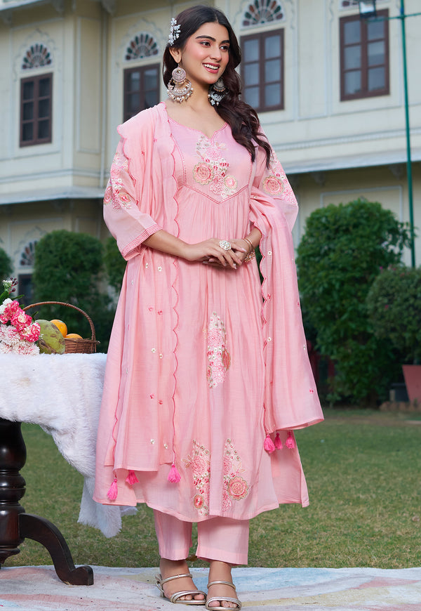 Woman in a pink traditional outfit standing outdoors with a decorative background