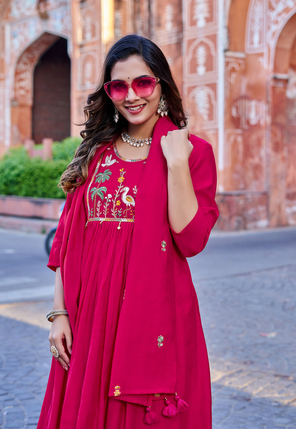 Woman in a red traditional outfit with embroidery standing in front of a historic building.