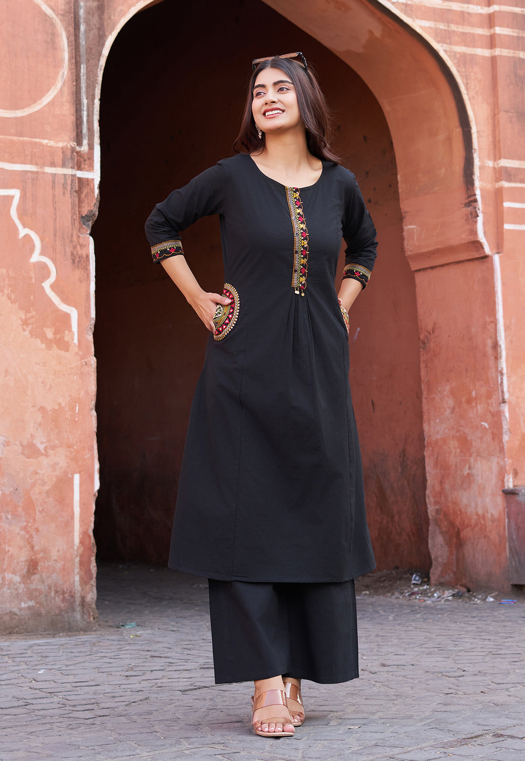 Woman in a black traditional outfit standing in front of an archway.