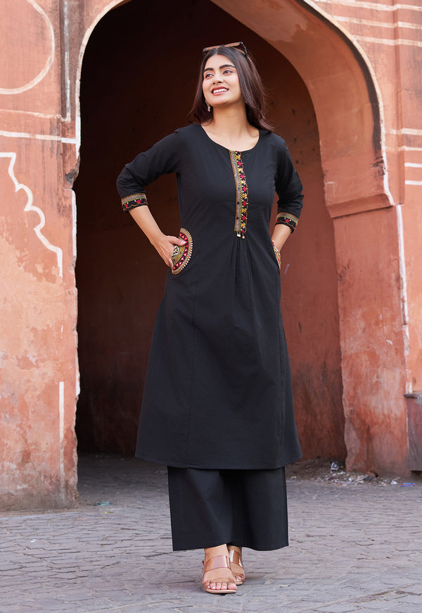 Woman in a black traditional outfit standing in front of an archway.