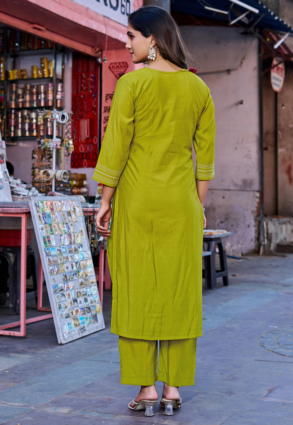 A woman wearing a bright olive green kurta and matching palazzo pants, photographed from behind in an outdoor street market setting.